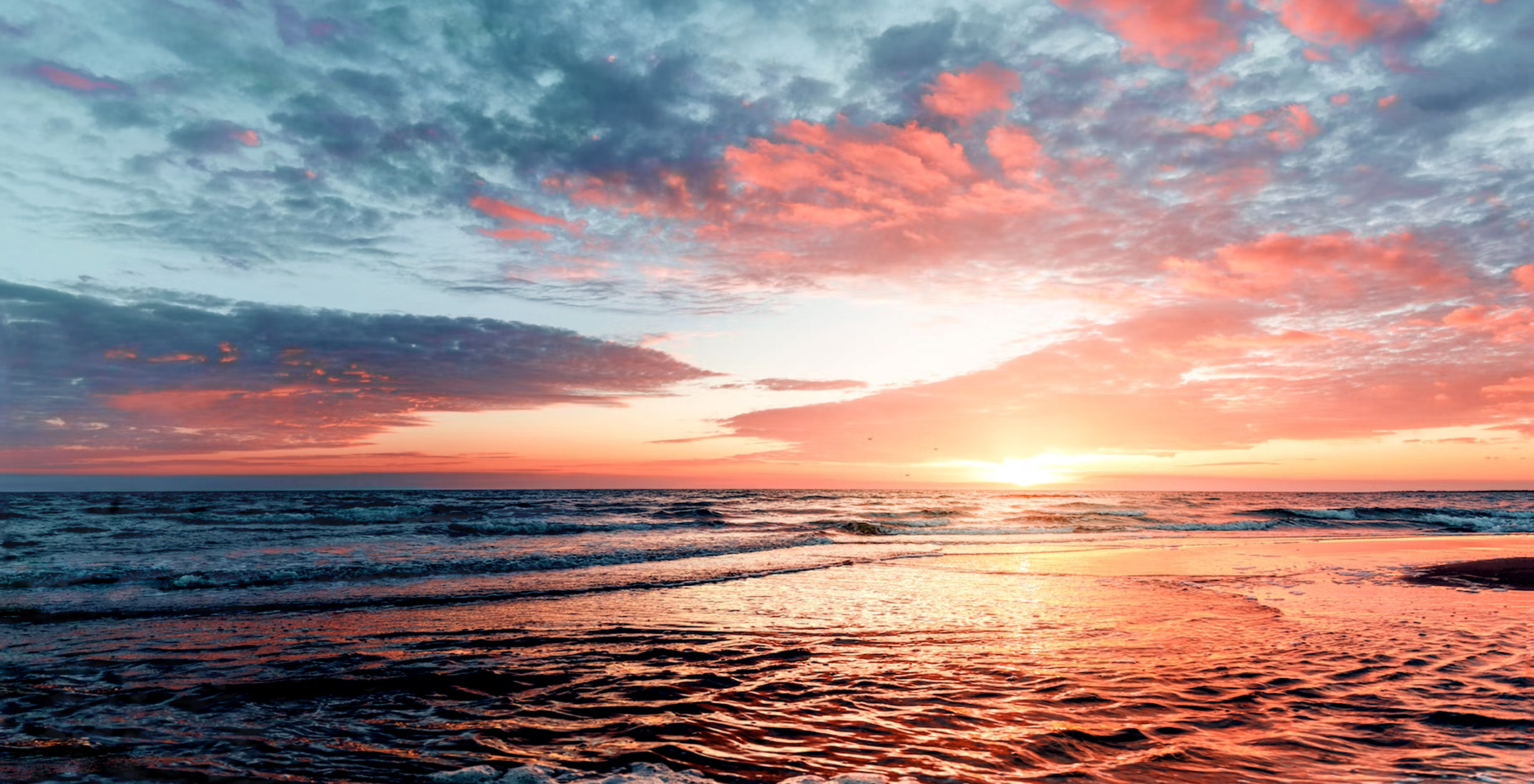 a sunset over the ocean with pink clouds in the sky