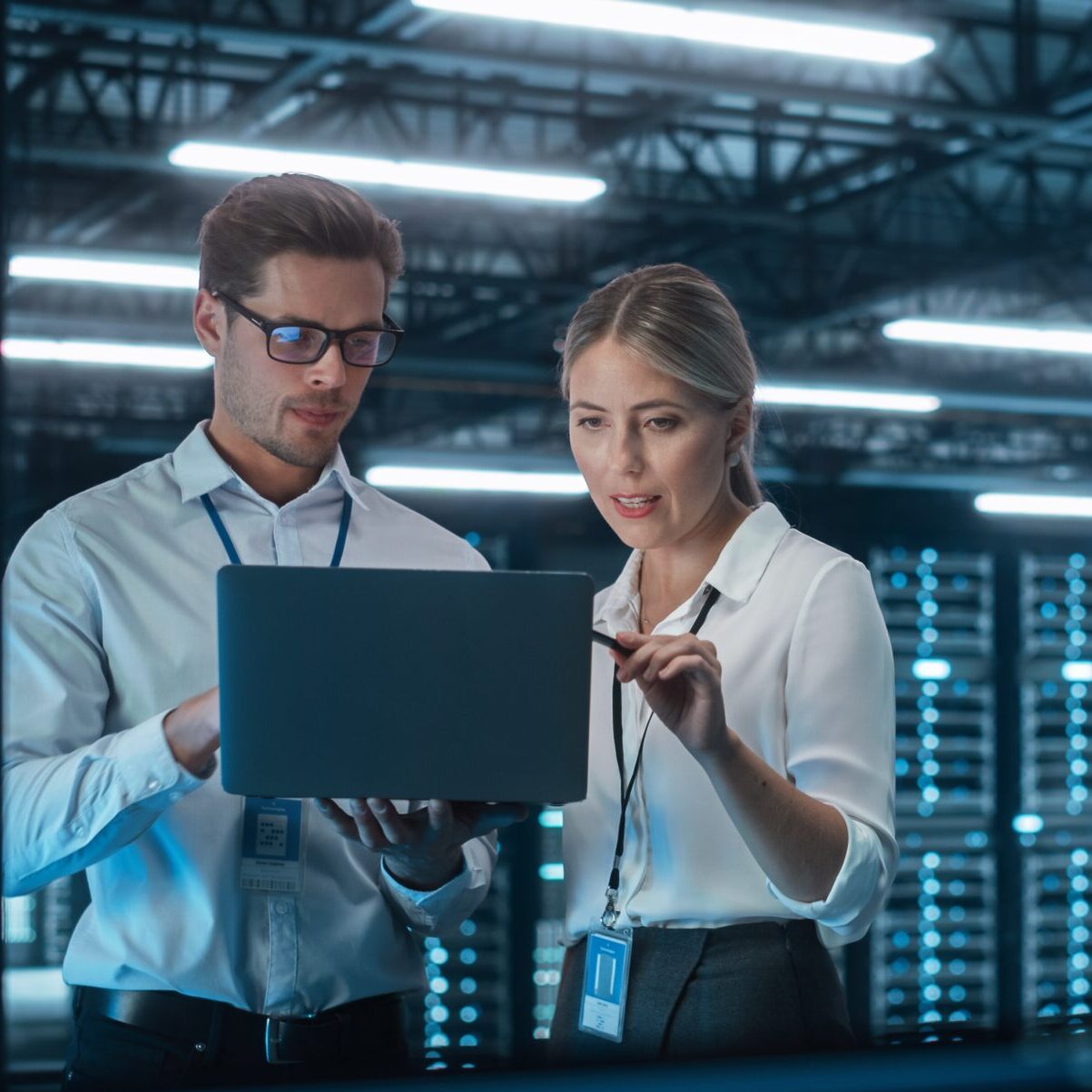 a man and a woman are looking at a laptop together