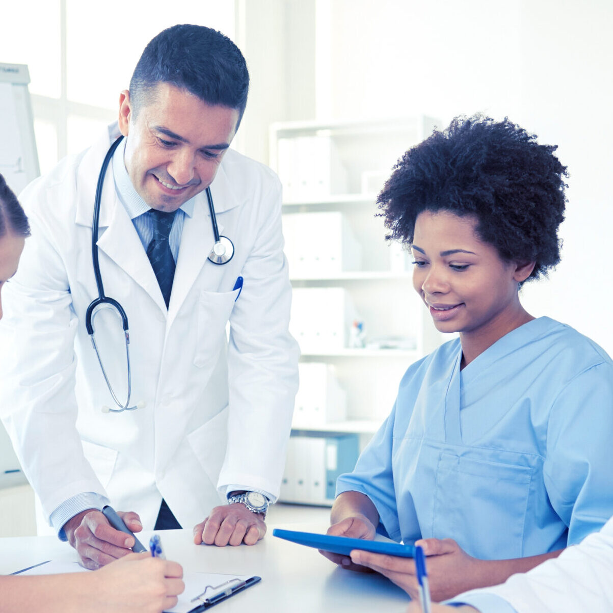 a group of doctors and nurses are looking at a tablet